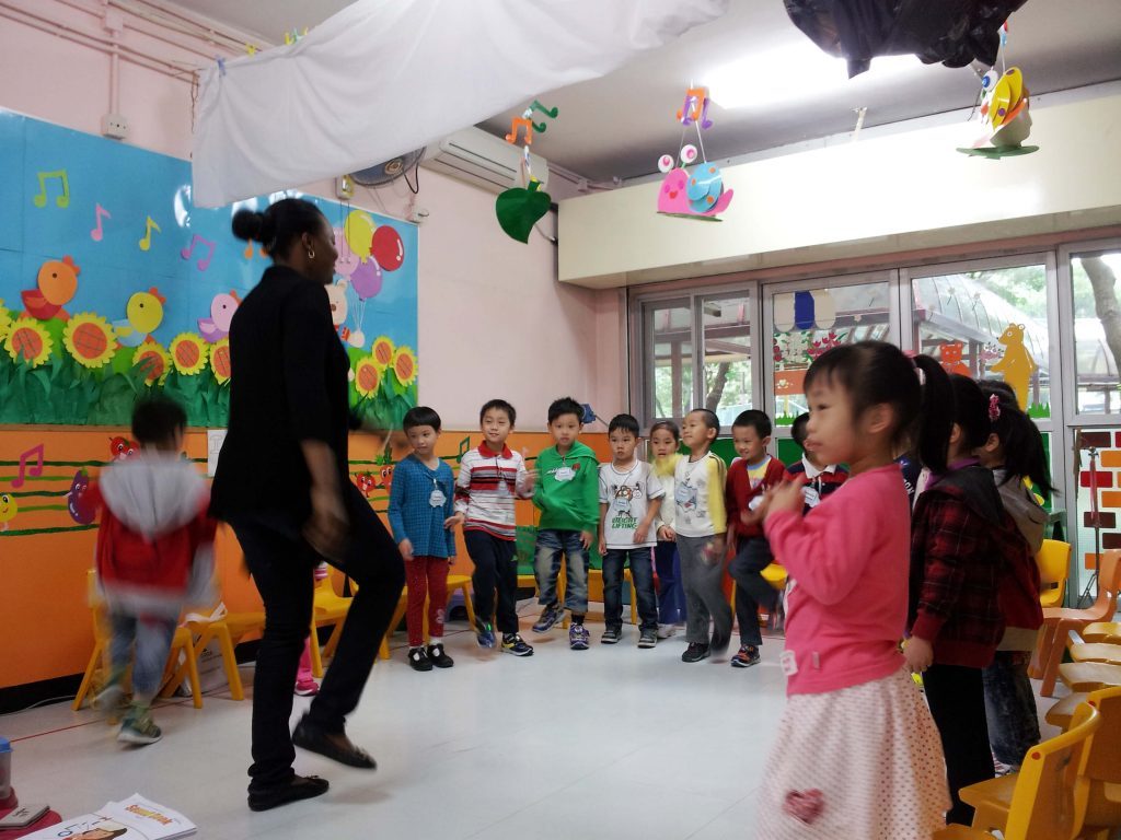 ESL teacher demonstrating dance movements in front of a group of kindergarten students